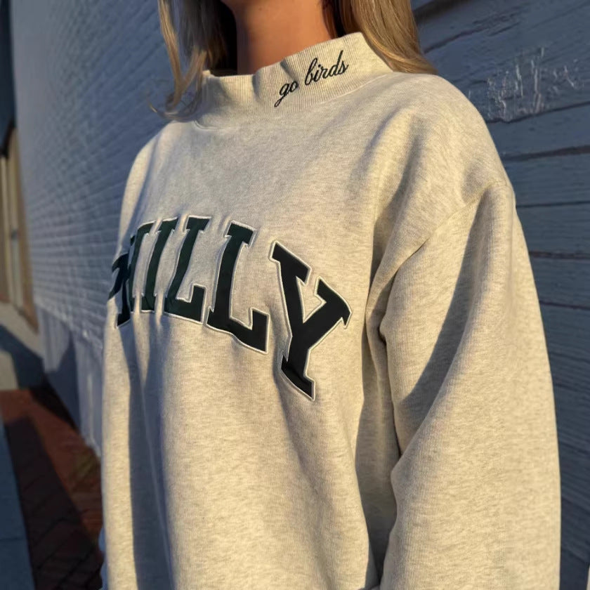 Dame med vid skåret college-sweatshirt med høj krave og påsyet skrift Skovae