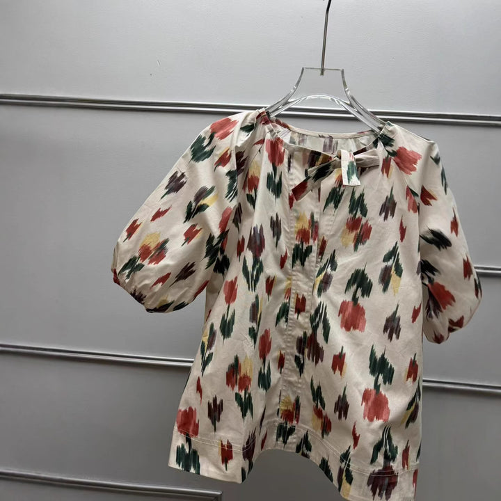 Damebluse med dekorativt sløjfekrave og florale mønstre Stilla