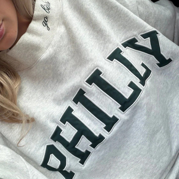 Dame med vid skåret college-sweatshirt med høj krave og påsyet skrift Skovae