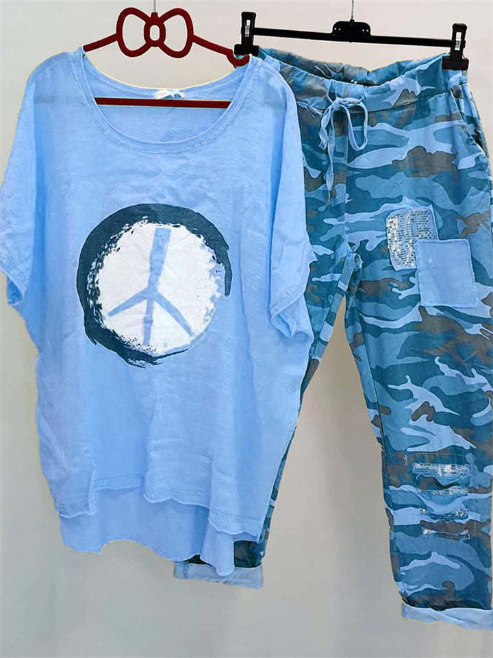 Damer med et afslappet fritidssæt med løst skåret linned-look t-shirt, fredssymbol og camouflage-joggingbukser med patchdetaljer Skovae