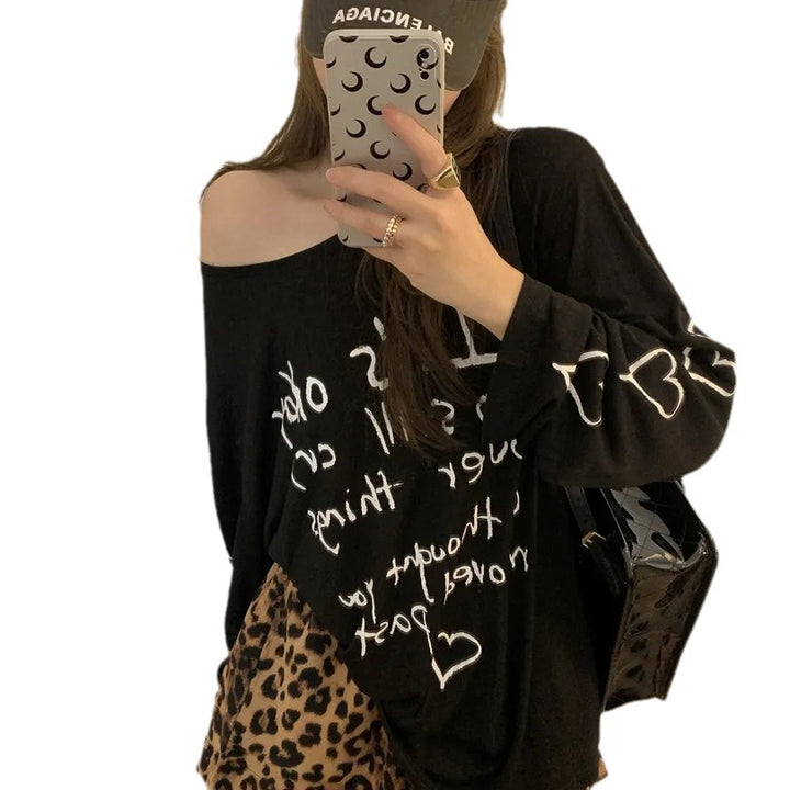 Kvinders afslappede oversized top med off-shoulder design og kunstnerisk skrifttype Stilla