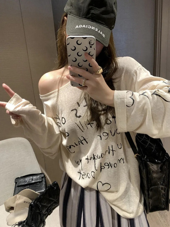 Kvinders afslappede oversized top med off-shoulder design og kunstnerisk skrifttype Stilla