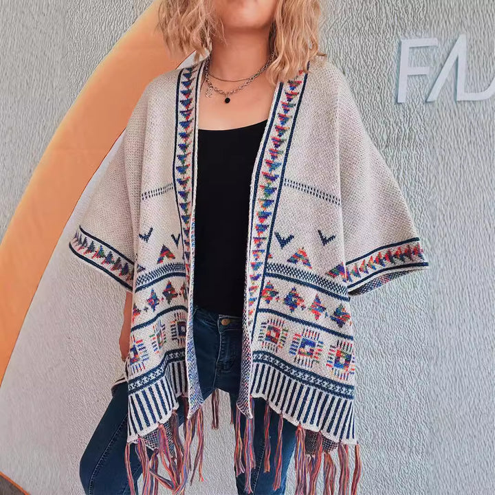 Damer fashionabel strikket poncho med frynset kant og farverigt mønster Stilla