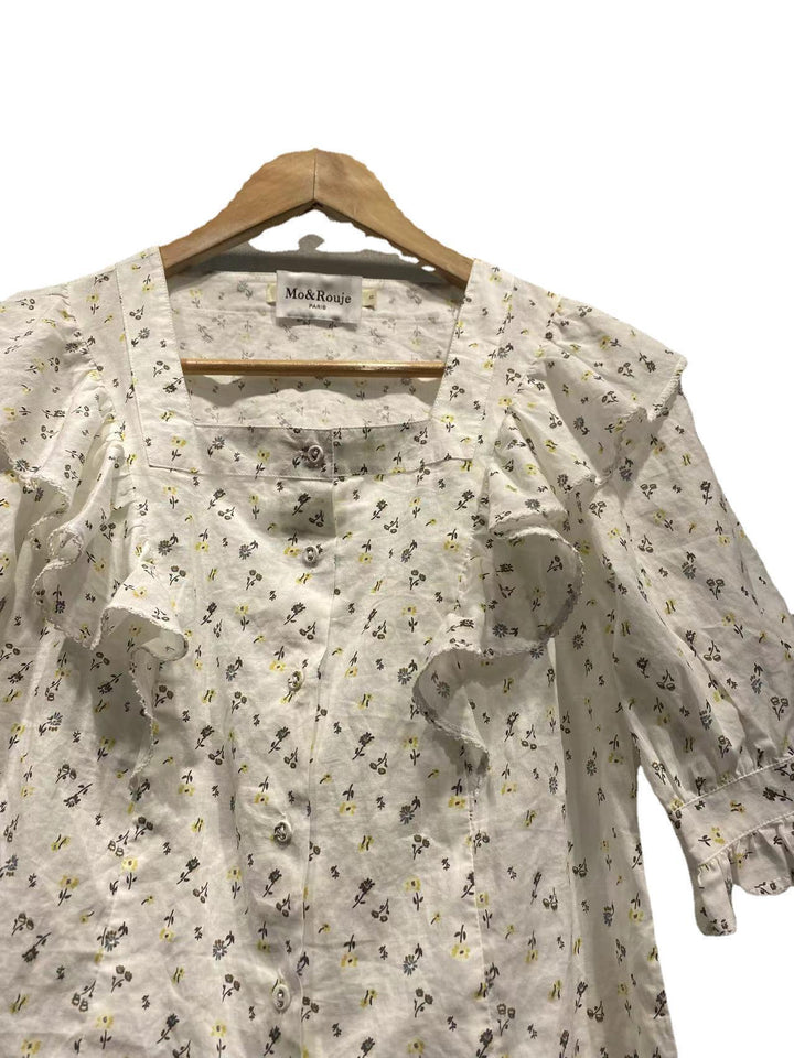 Damebluse med elegante flæsedetaljer og blomstret mønster Stilla