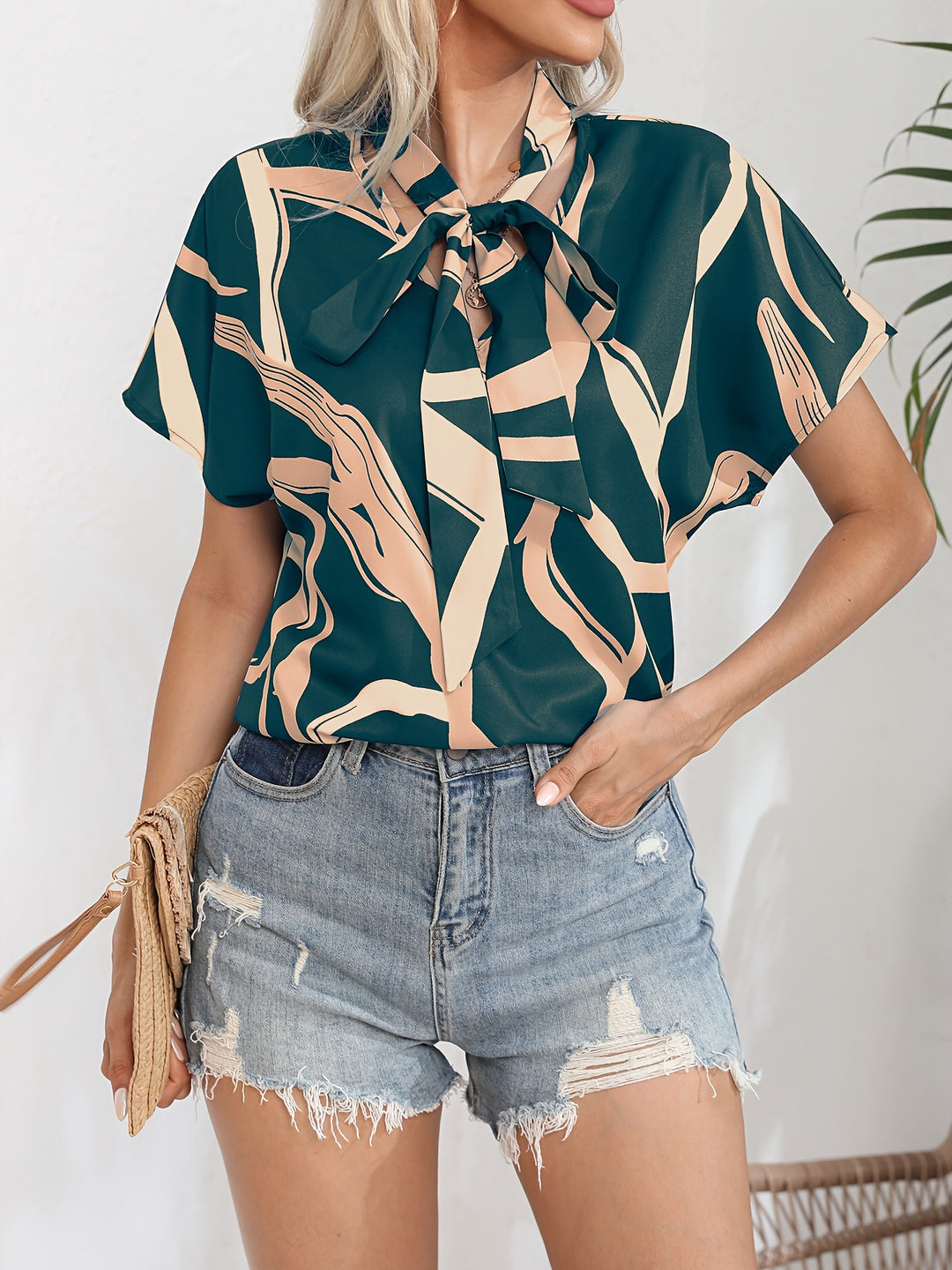 Damebluse med flot sløjfekrave og moderne grafisk design Stilla