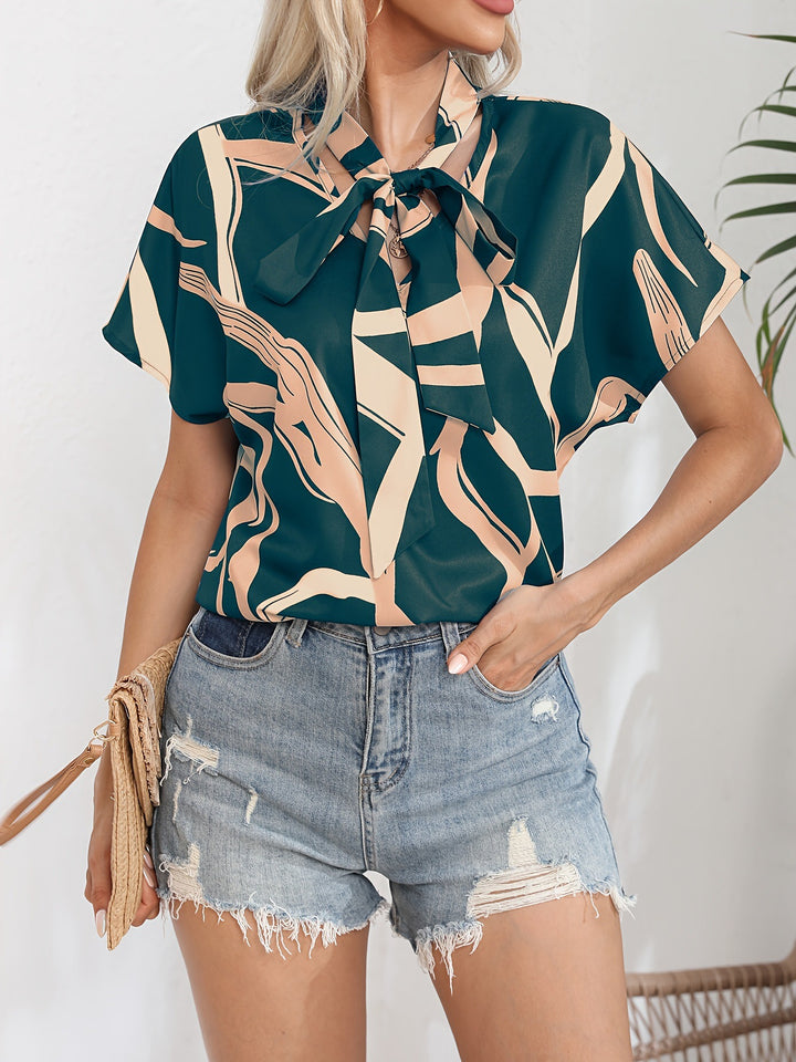 Damebluse med flot sløjfekrave og moderne grafisk design Stilla